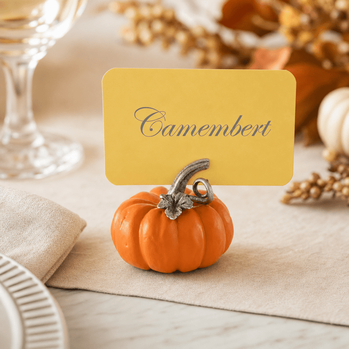 Pumpkin place card holder labeling Camembert on a fall table with gourds and a crystal glass