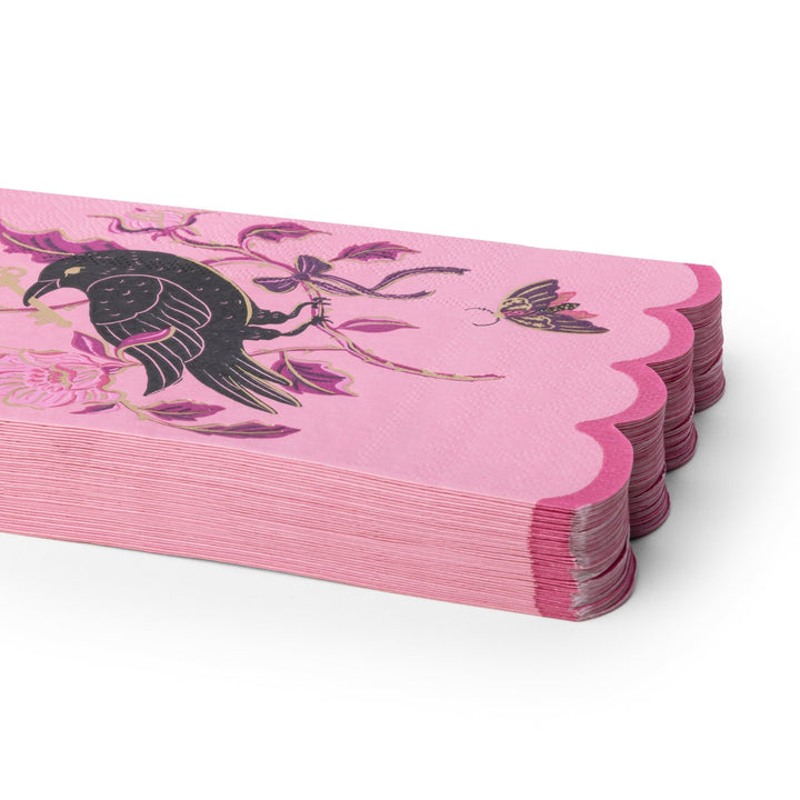 A stack of pink paper napkins with scalloped edges, decorated with a black raven, pink flowers, and a butterfly on a white background.