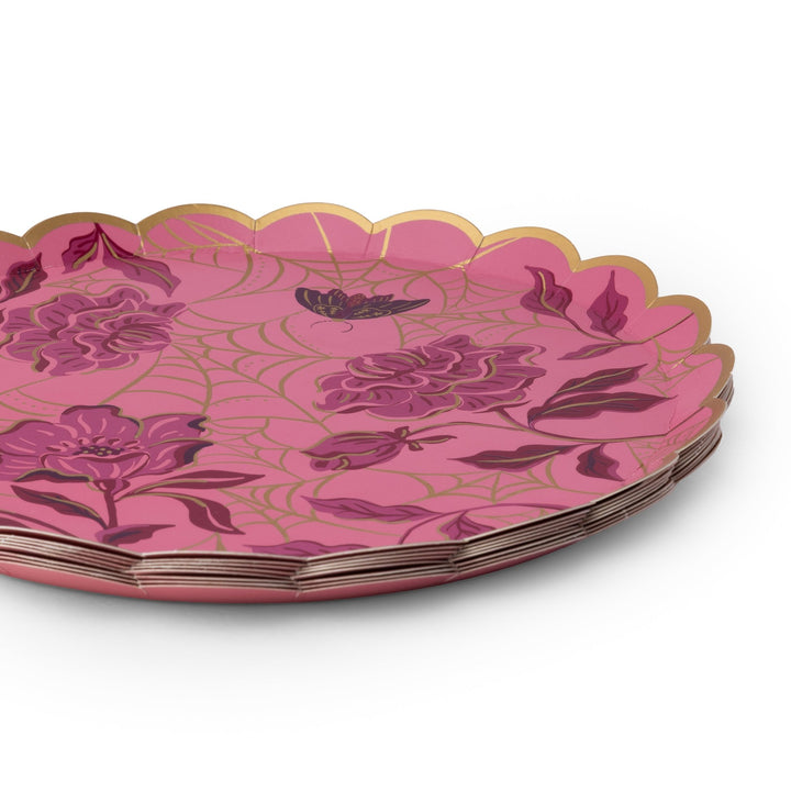 Stack of pink spider-web cake plates with gold scalloped rims for a Halloween dessert table