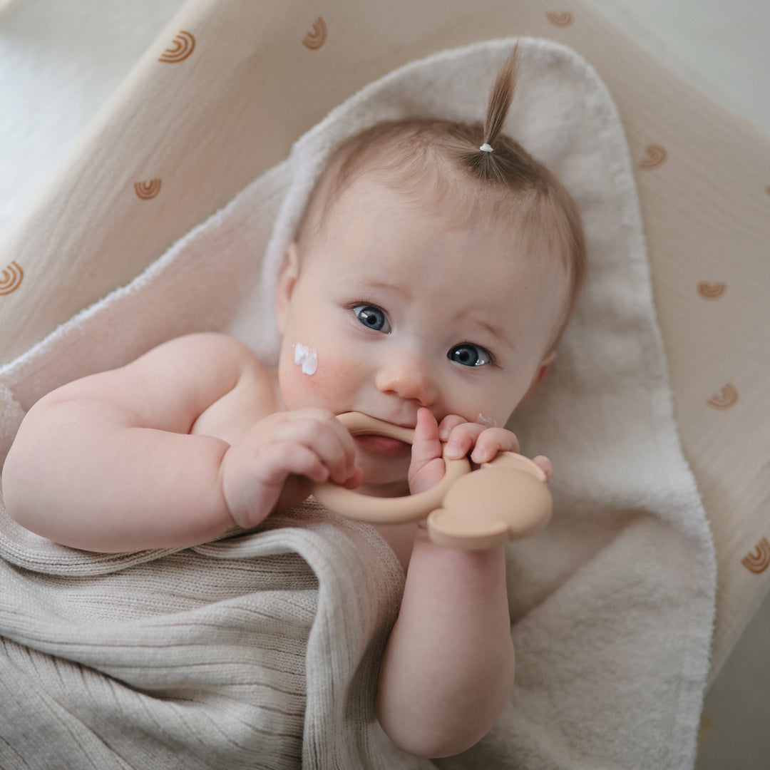 Baby holding a Mushie animal ring teether