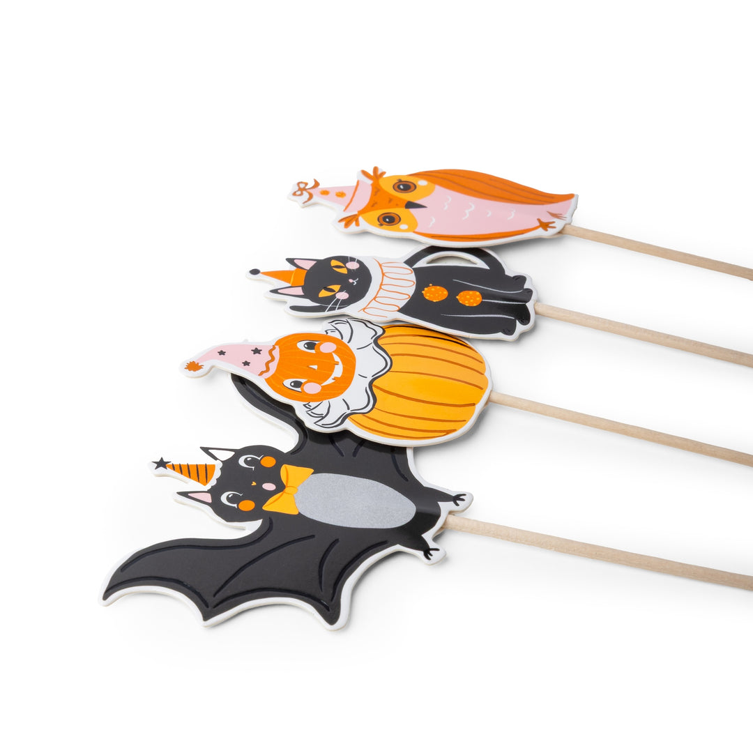 Four Halloween-themed paper cutout sticks featuring a bat, pumpkin, cat, and owl in festive costumes, arranged diagonally on a white background.