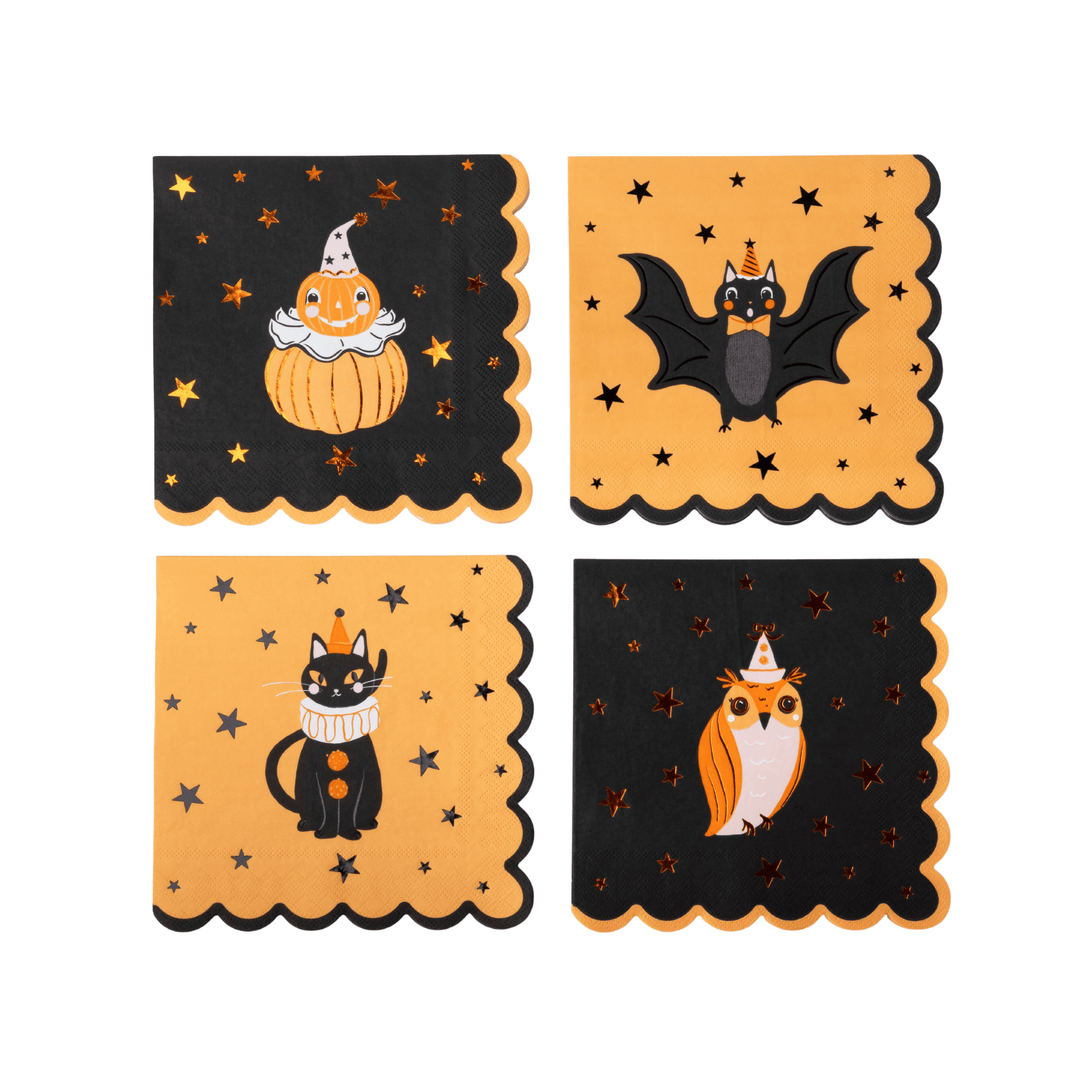 Four Halloween-themed paper napkins arranged on a white background. The top-left napkin is black with an orange jack-o'-lantern and gold stars; the top-right is orange with a black bat and gold stars; the bottom-left is orange with a black cat and gold stars; the bottom-right is black with an orange owl and gold stars.