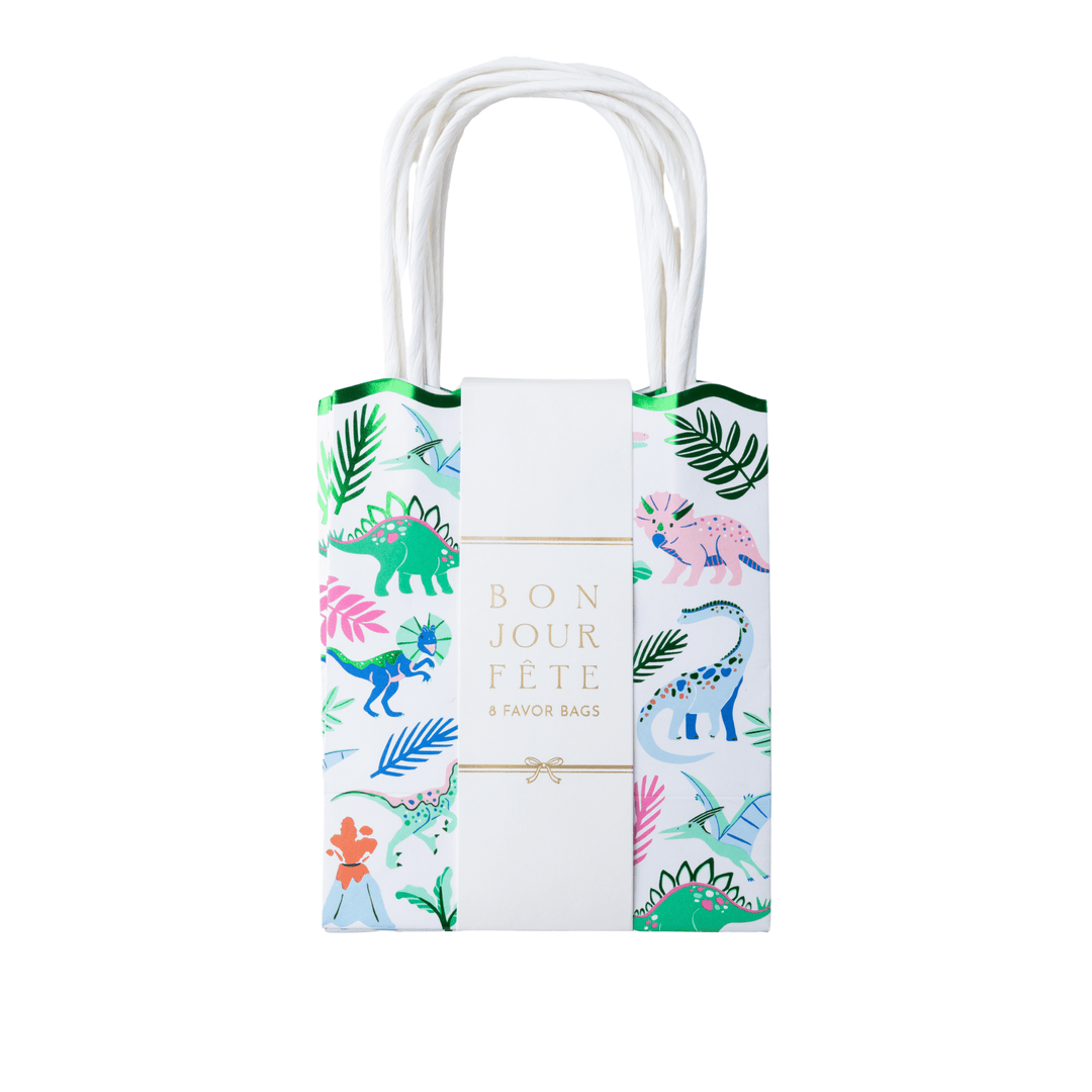 Set of 8 dinosaur favor bags wrapped in a Bonjour Fête band, with green scalloped tops and a colorful dino print