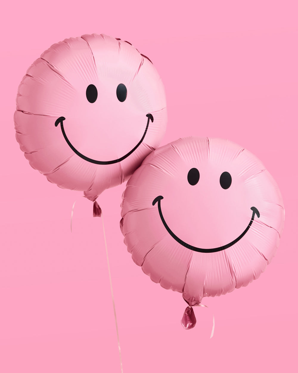 Two pink smiley face balloons