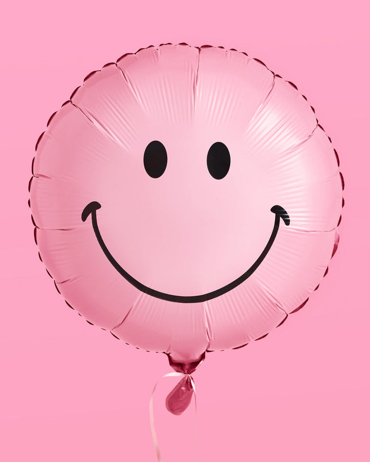 Pink smiley face balloons styled at a party