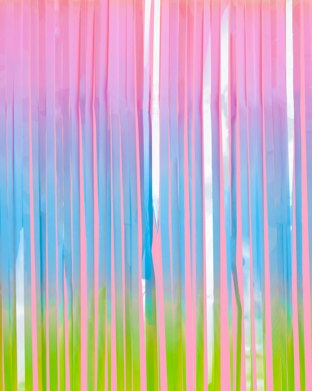 Pastel rainbow fringe strands in pink, blue, and green catching light at close range