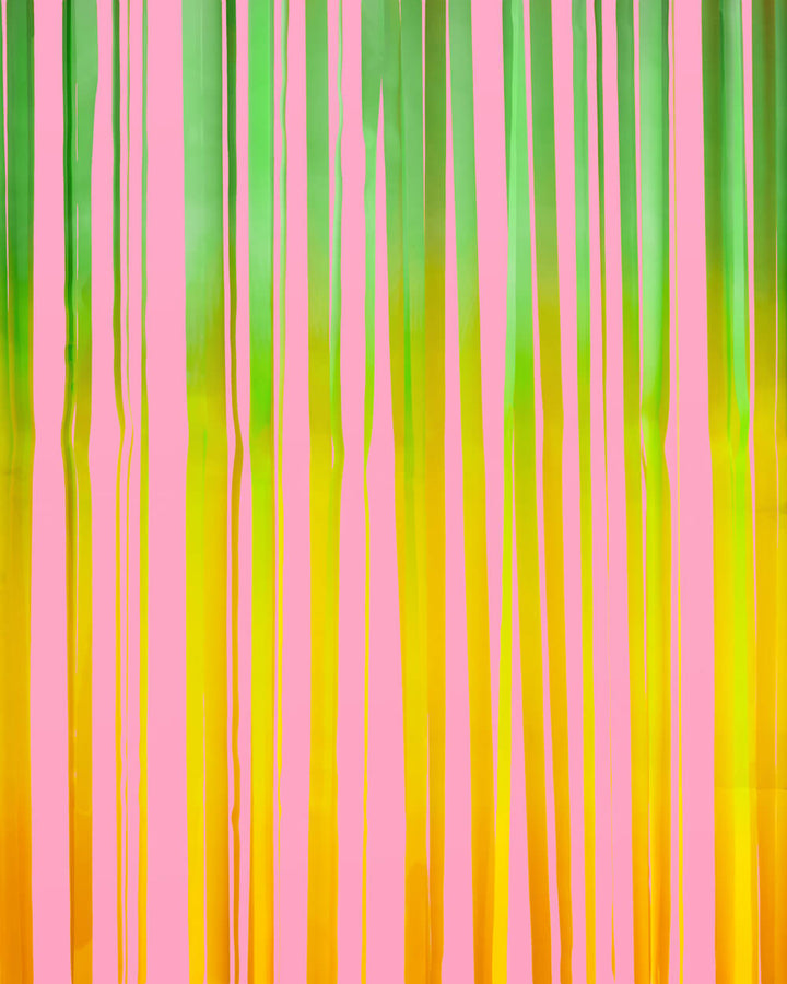 Close-up of pastel green, yellow, and pink fringe strands on a rainbow curtain backdrop