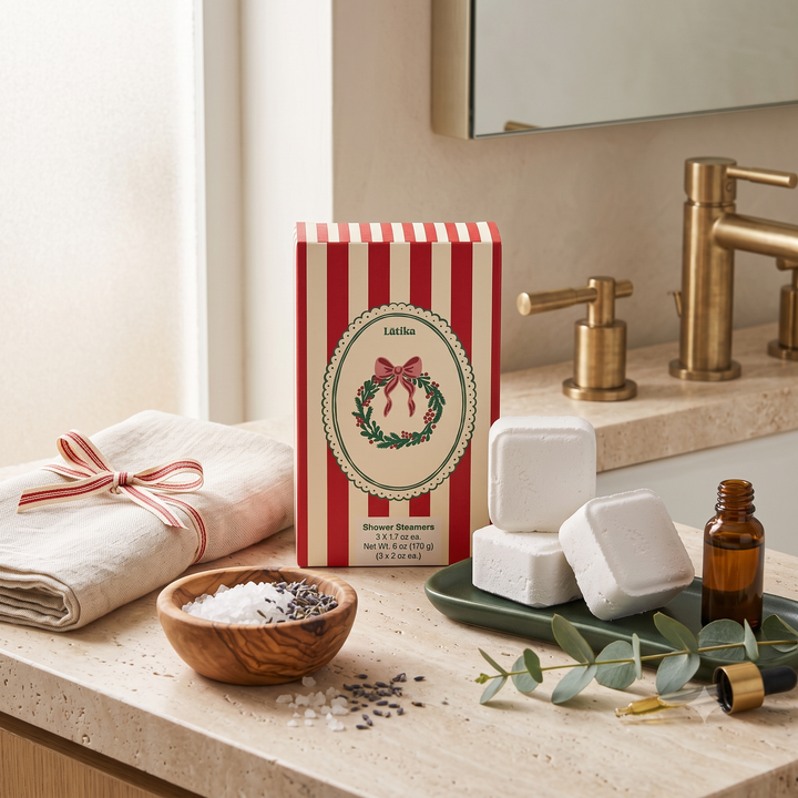 Shower steamer box with white cubes, lavender salts and an oil bottle on a travertine counter for a holiday spa night