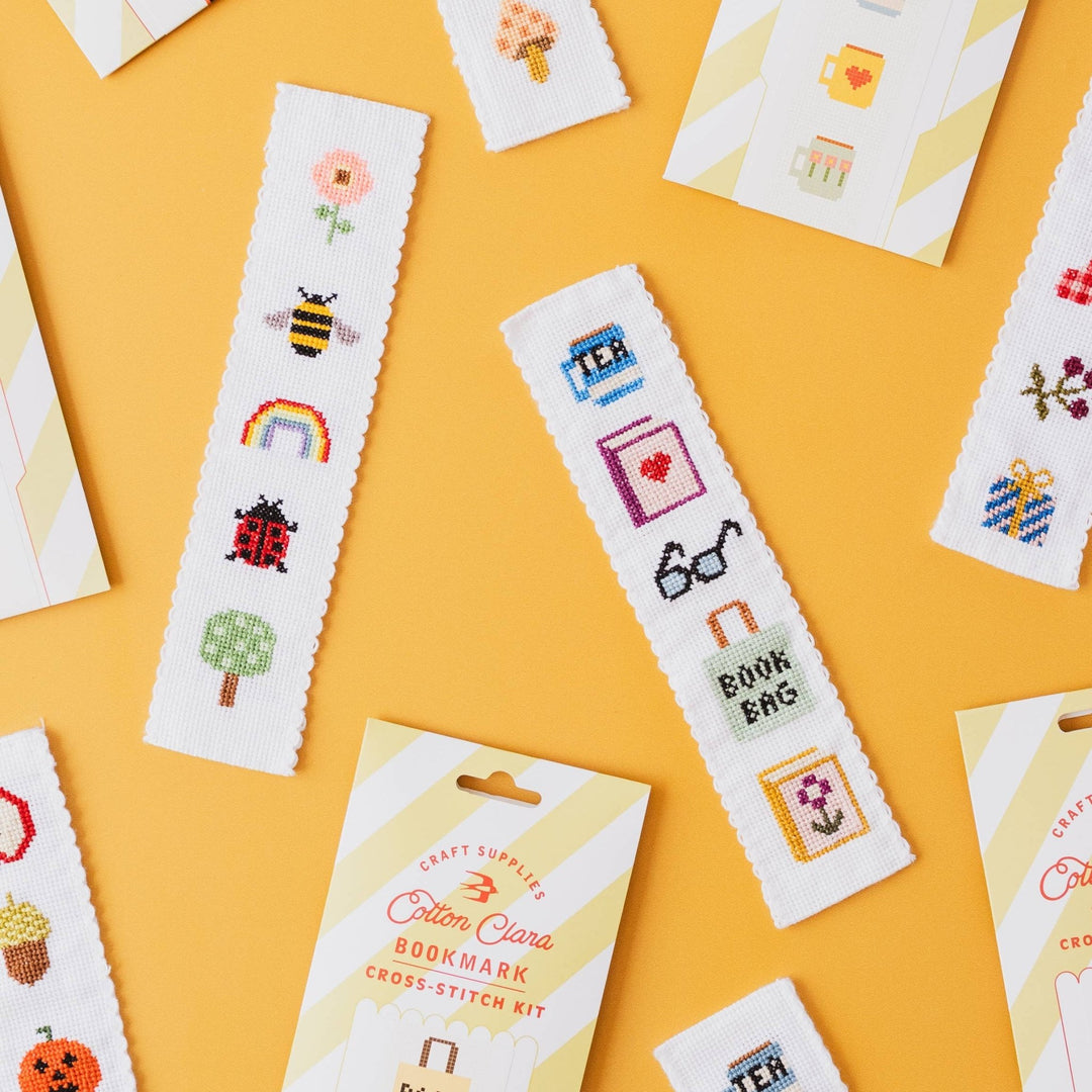 Christmas and nature cross stitch bookmark kits scattered on a yellow background