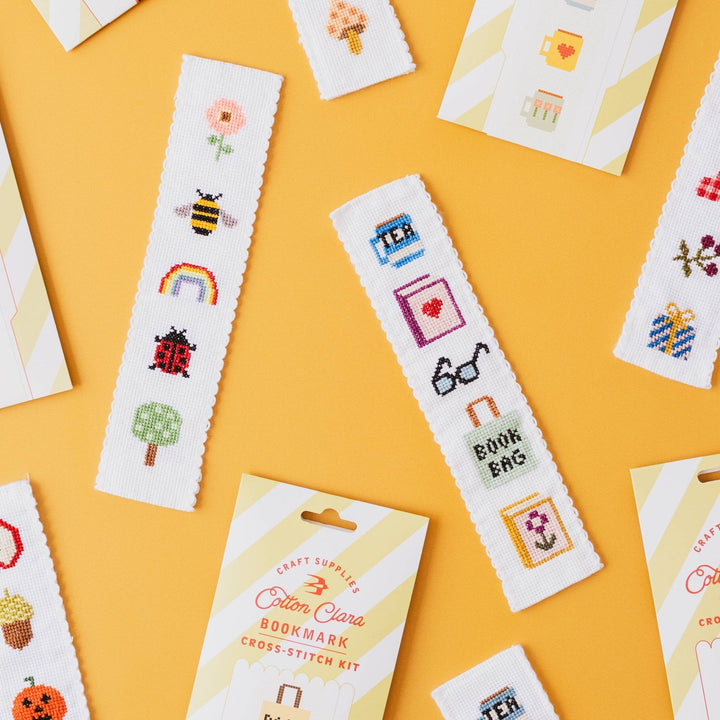 Christmas and nature cross stitch bookmark kits scattered on a yellow background