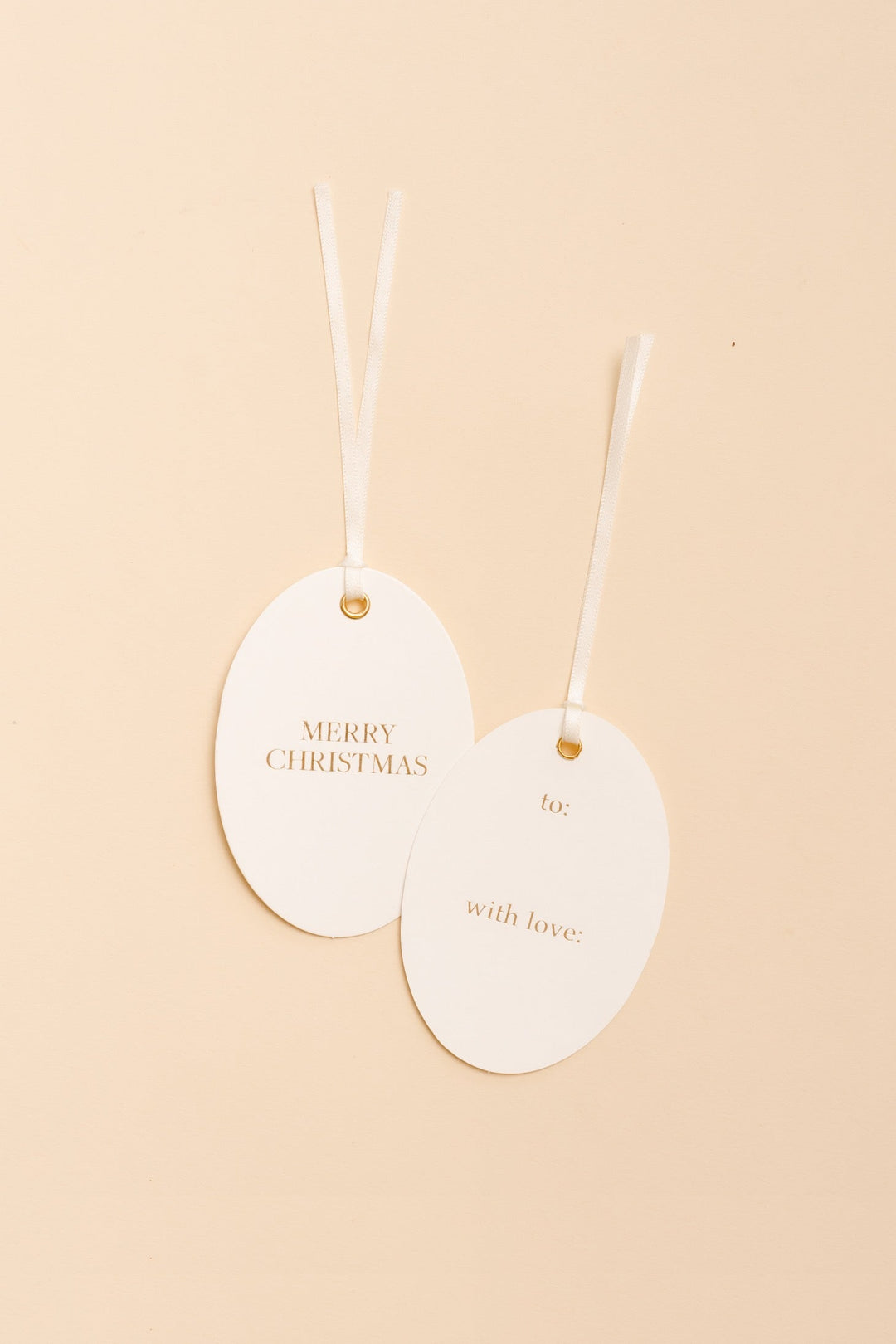 Two oval letterpress gift tags on cream, gold foil Merry Christmas on one and to and with love on the other