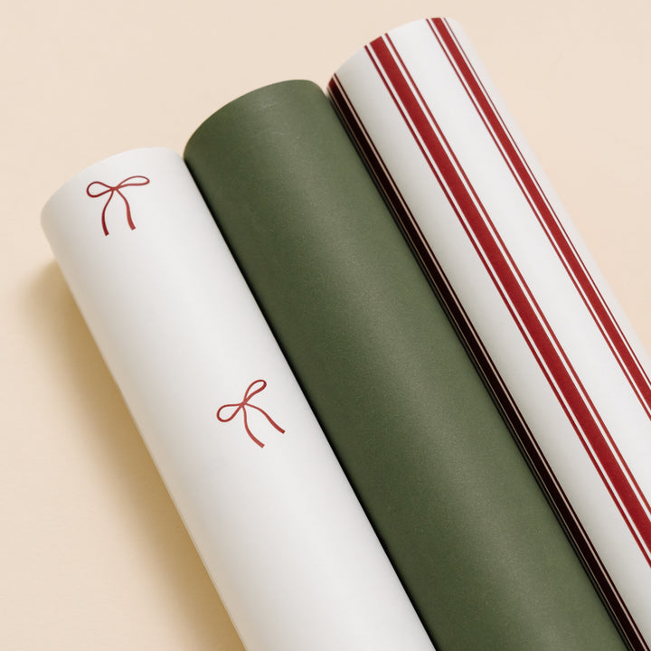 Close-up of white bow print, soft green, and red candy stripe wrapping paper rolls