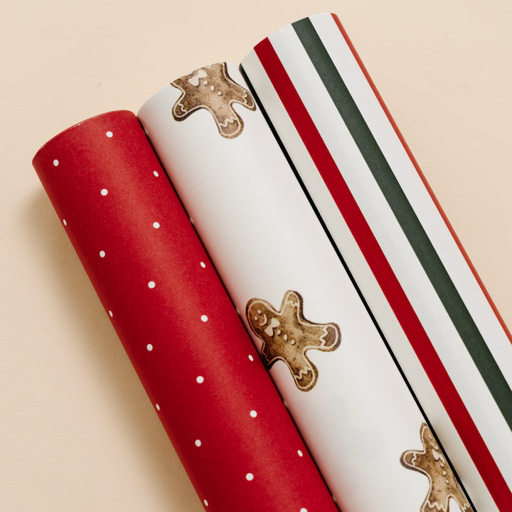 Close-up of red polka dot, gingerbread print, and red and green stripe wrapping paper rolls