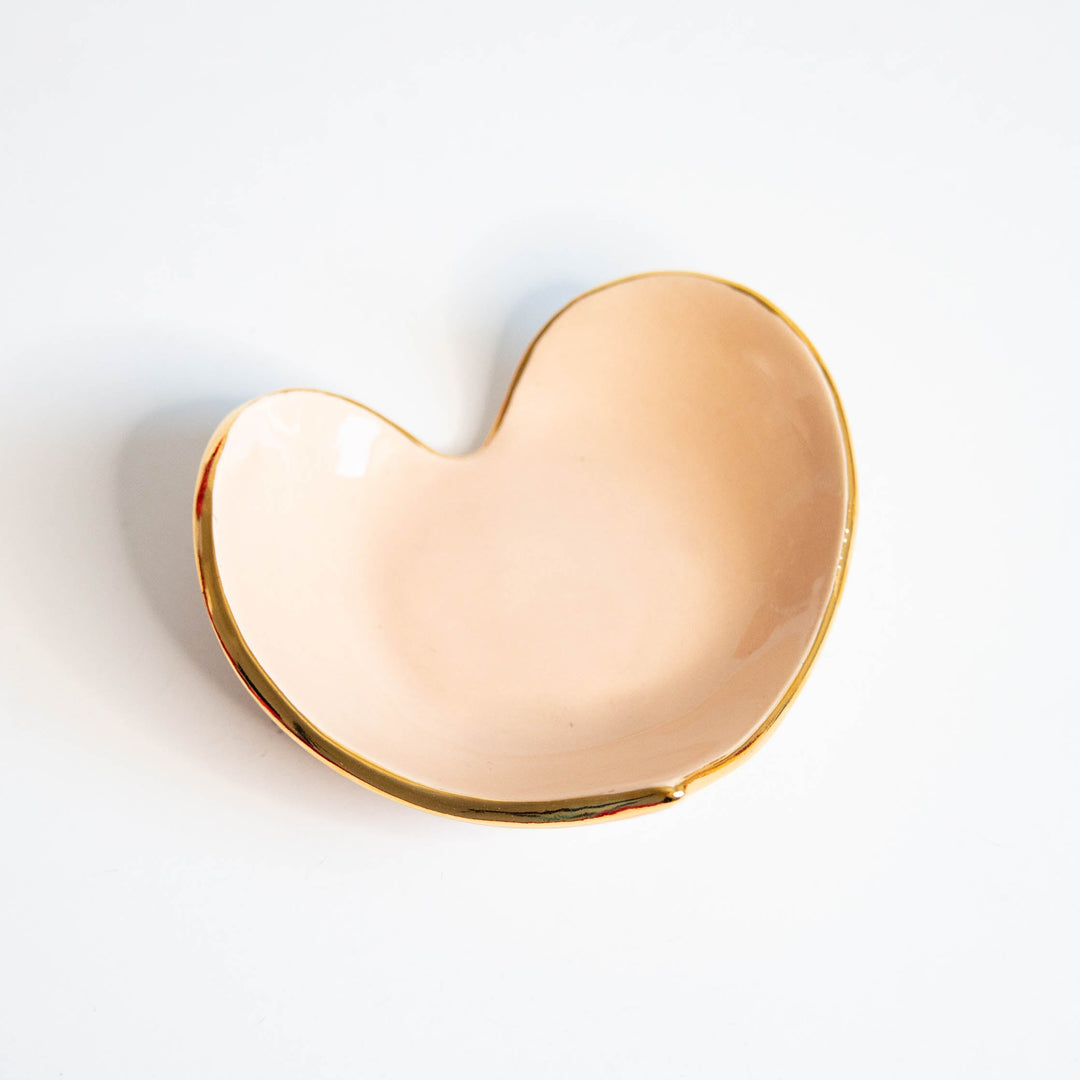 Peach heart ring dish with a gold rim, side angle on white