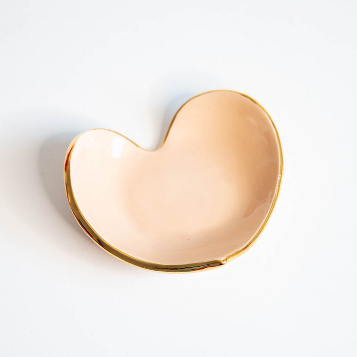 Peach heart ring dish with a gold rim, side angle on white