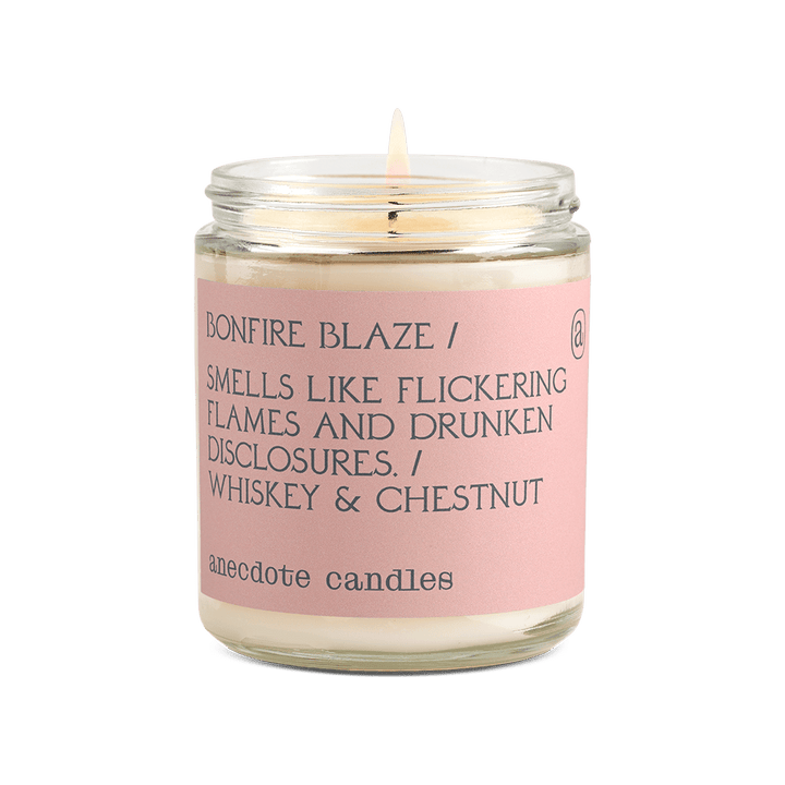 Lit Bonfire Blaze glass jar candle with a blush pink label reading whiskey and chestnut