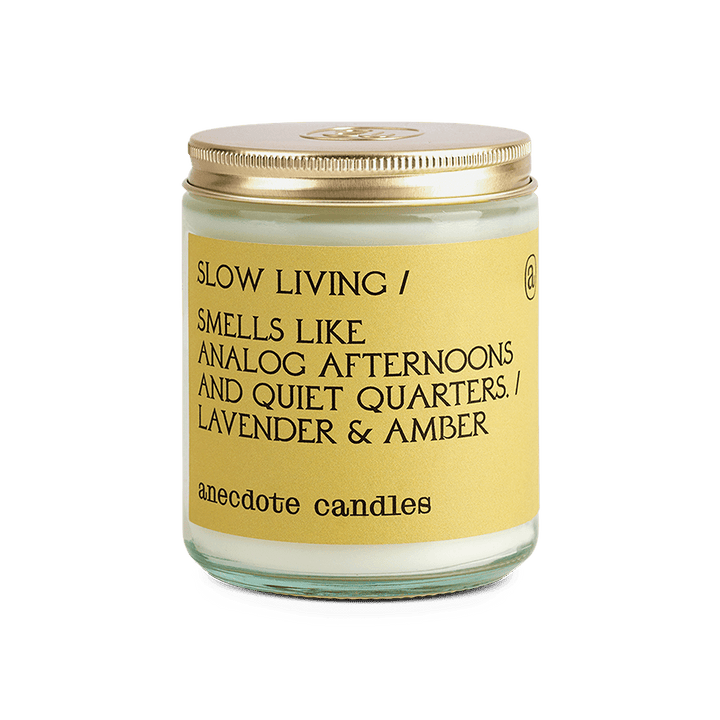 Slow Living lavender and amber candle in a clear glass jar with a yellow label and gold lid