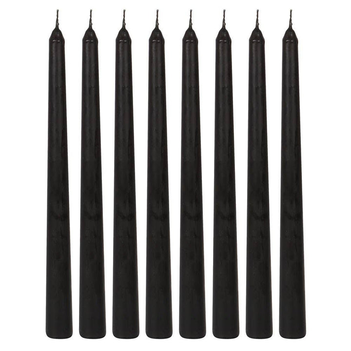 Eight unlit black taper candles lined up in a row, ready to bleed red at a Halloween gathering