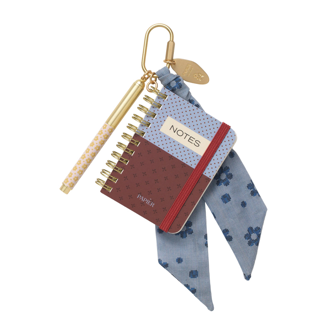 Pocket Notes notebook bag charm with blue floral ribbon, gold carabiner, and mini pen, a giftable accessory
