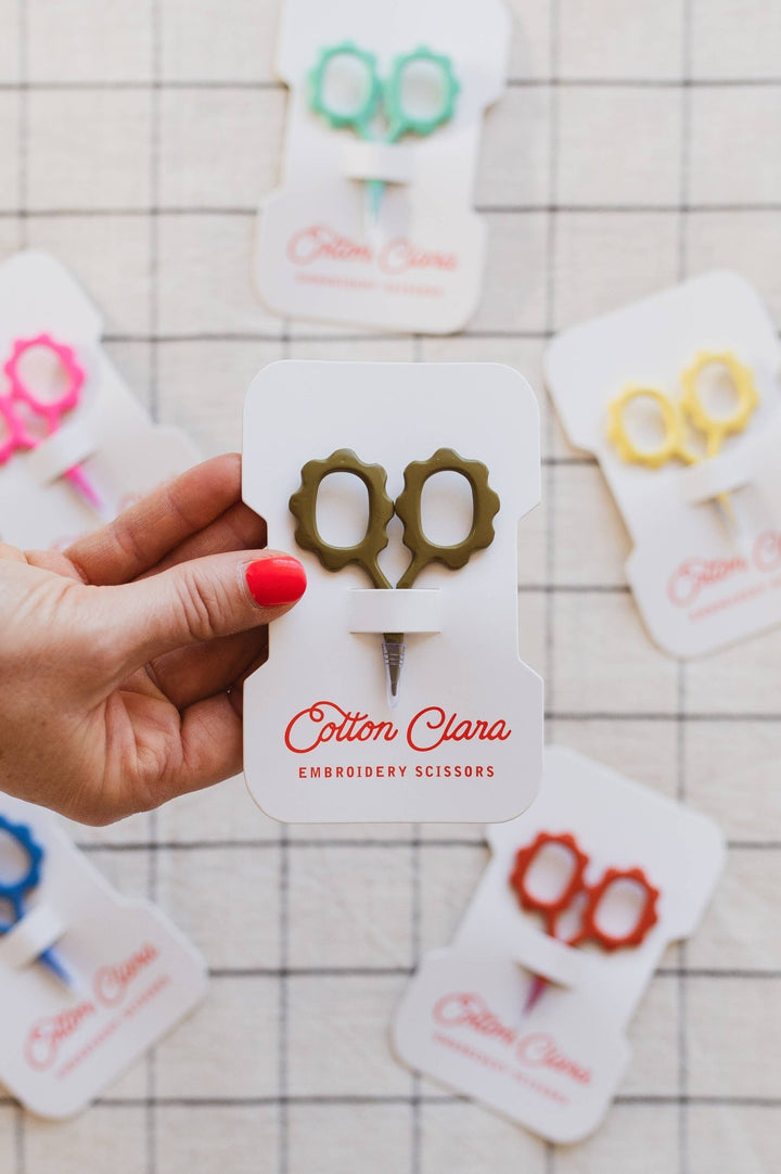 Hand holding the olive flower embroidery scissors card above more colorways