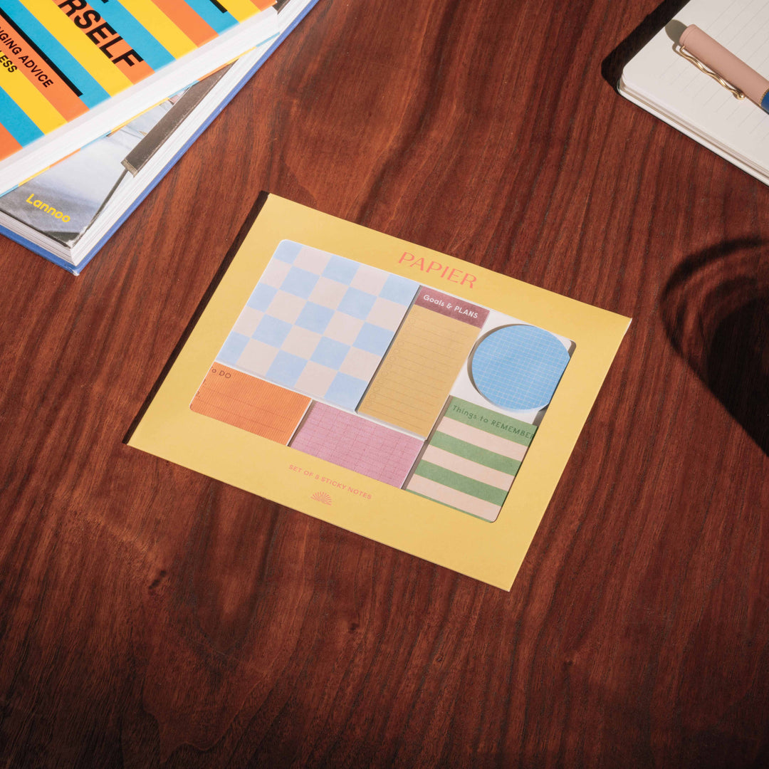 Sticky note set in its yellow windowed envelope on a wood desk, a bright back to school pick