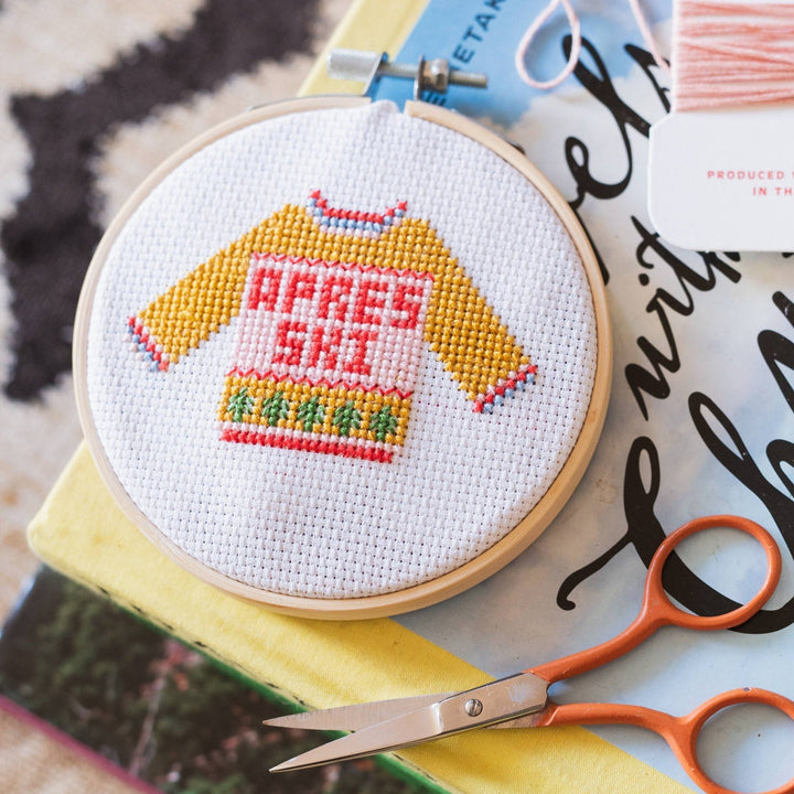 Finished apres ski sweater cross stitch hoop styled with orange embroidery scissors