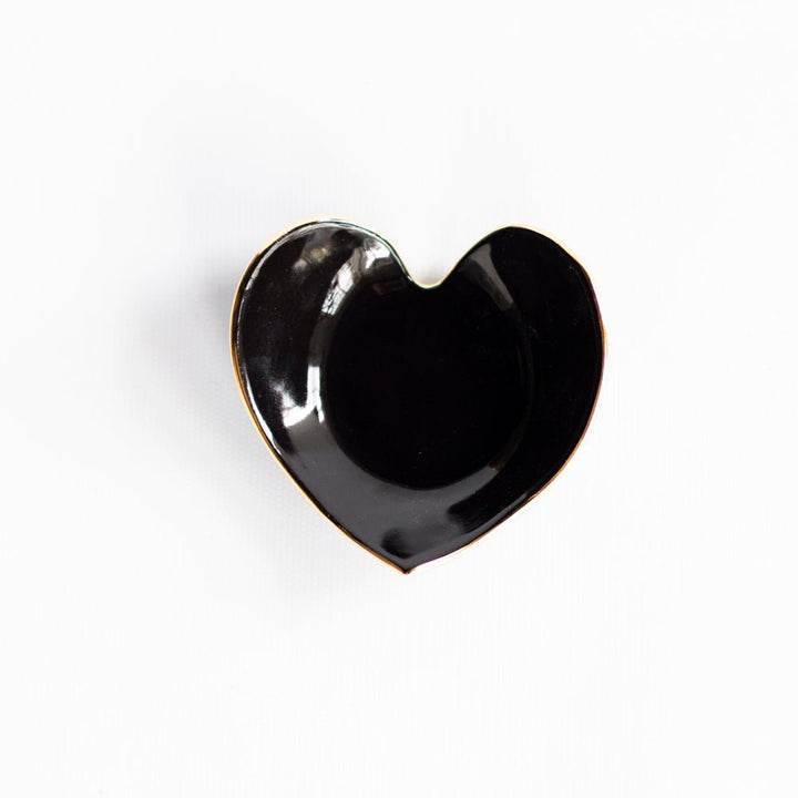 Glossy black heart ring dish with a gold rim on white