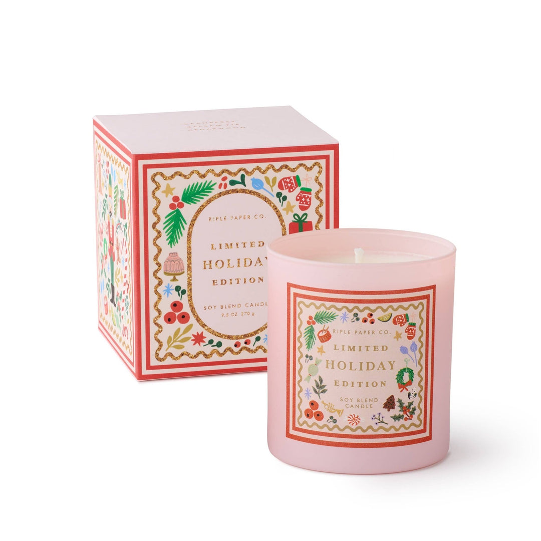 Holly Jolly Nutcracker holiday candle in pink glass with festive label beside gold glitter trimmed gift box