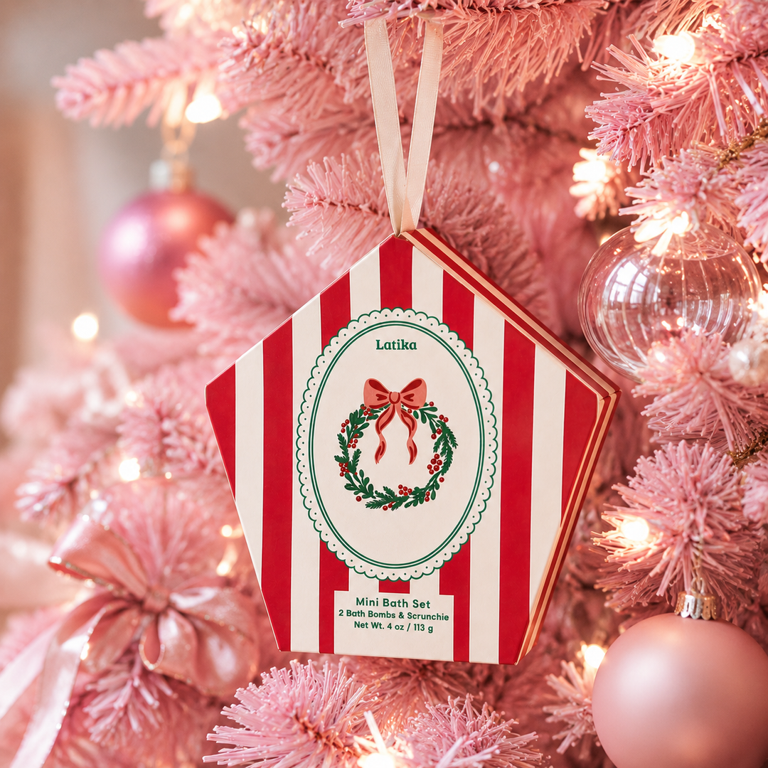 Red striped wreath box hanging on a pink flocked Christmas tree with glass ornaments