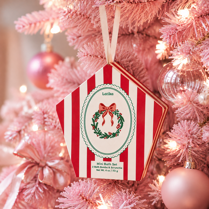 Red striped wreath box hanging on a pink flocked Christmas tree with glass ornaments