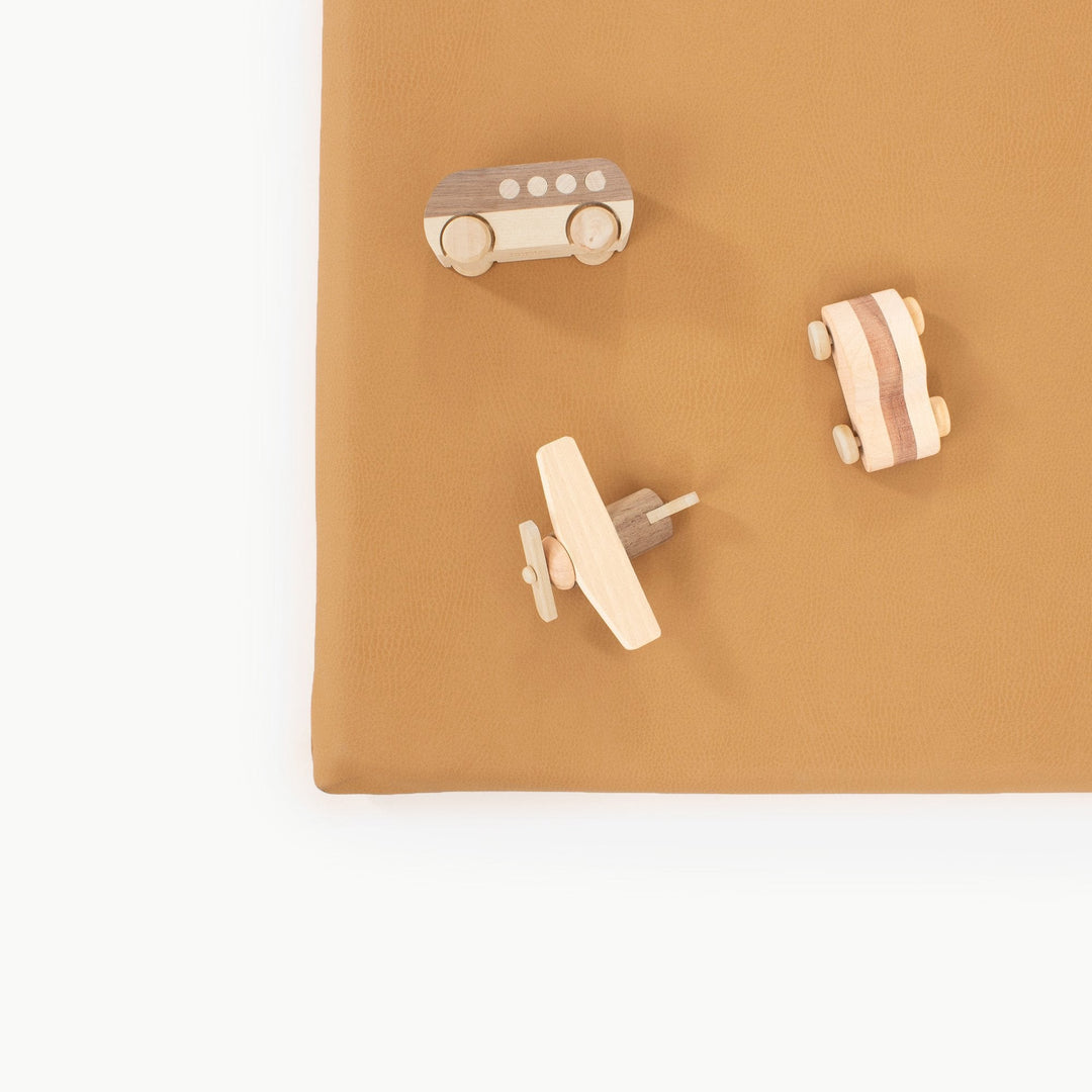 Overhead view of wooden toy vehicles on the camel vegan leather padded play mat