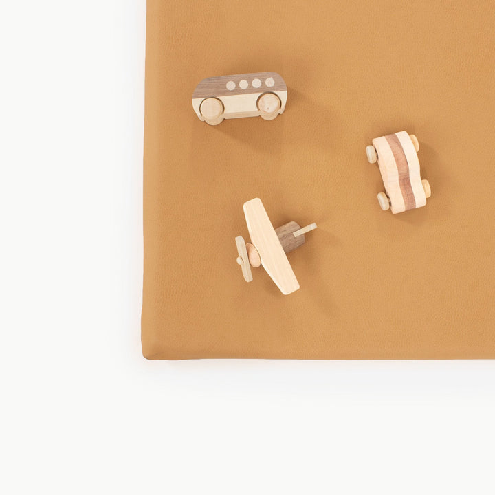 Overhead view of wooden toy vehicles on the camel vegan leather padded play mat
