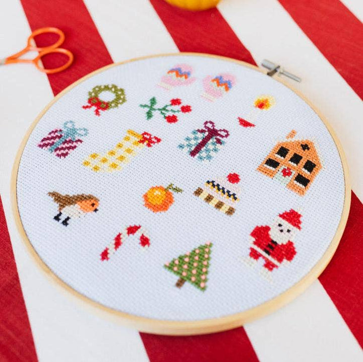 Colorful Christmas sampler cross stitch hoop with wreath, robin, and stocking motifs