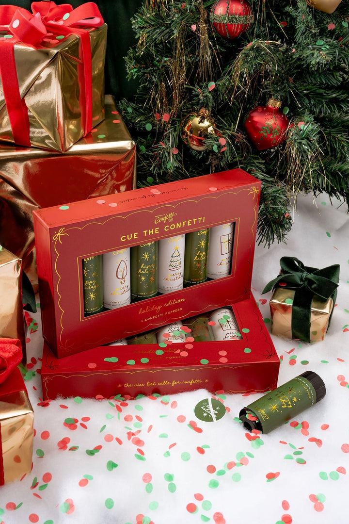 Open red Christmas confetti popper box under a tree, showing six red and green poppers