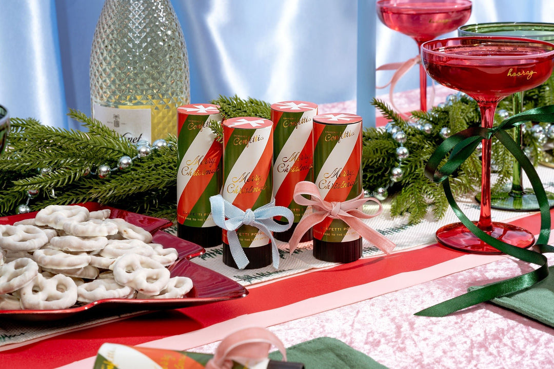 Red and white confetti poppers on a holiday table with a cranberry cocktail and yogurt pretzels