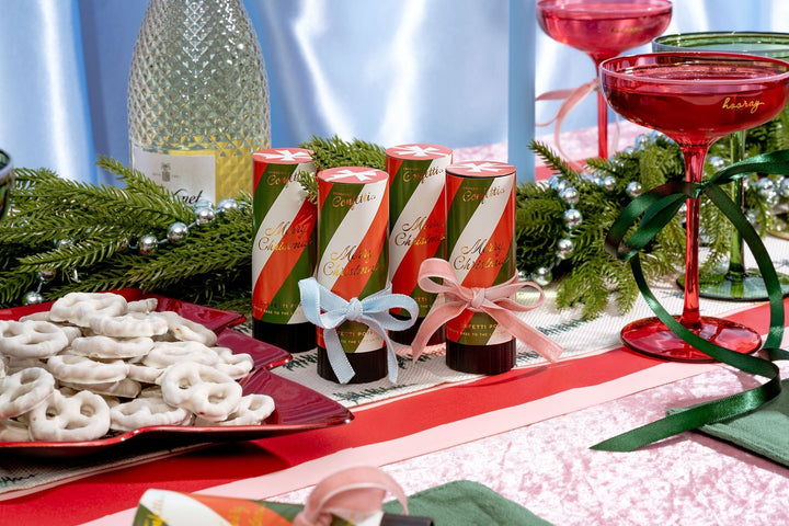 Red and white confetti poppers on a holiday table with a cranberry cocktail and yogurt pretzels