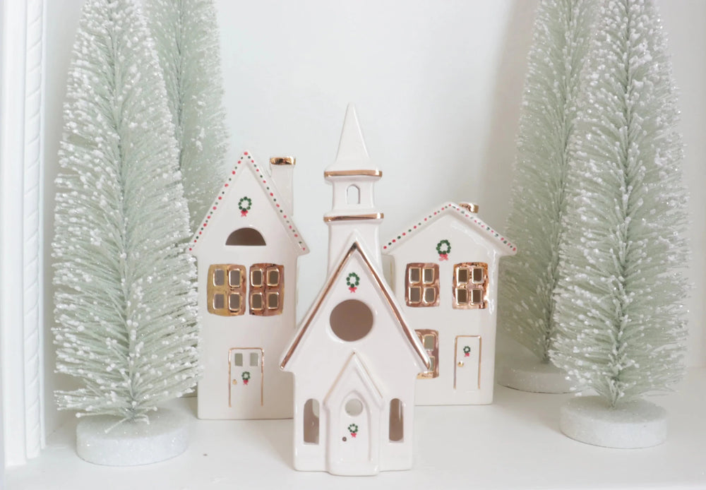 Ivory ceramic church and houses with gold trim between frosted sage bottle brush trees for Christmas mantel decor
