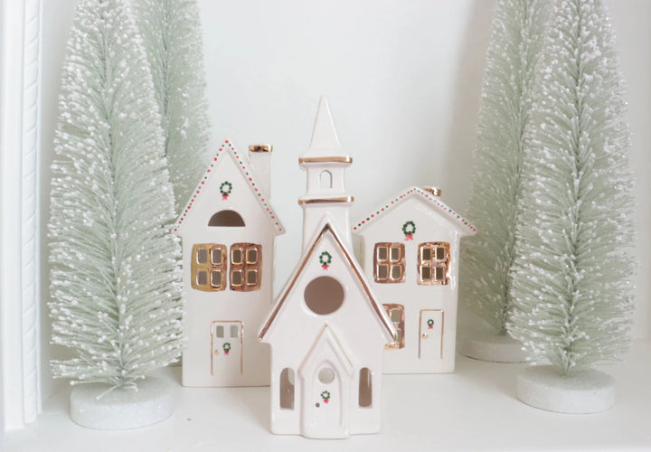 Ivory ceramic church and houses with gold trim between frosted sage bottle brush trees for Christmas mantel decor