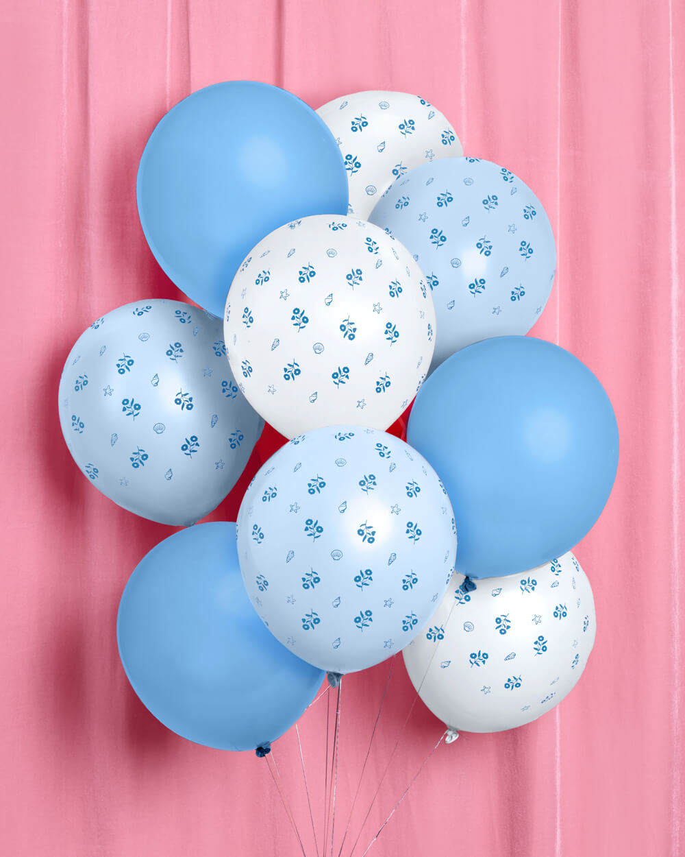 Blue and white coastal latex balloons styled on a sandy beach for a seaside party