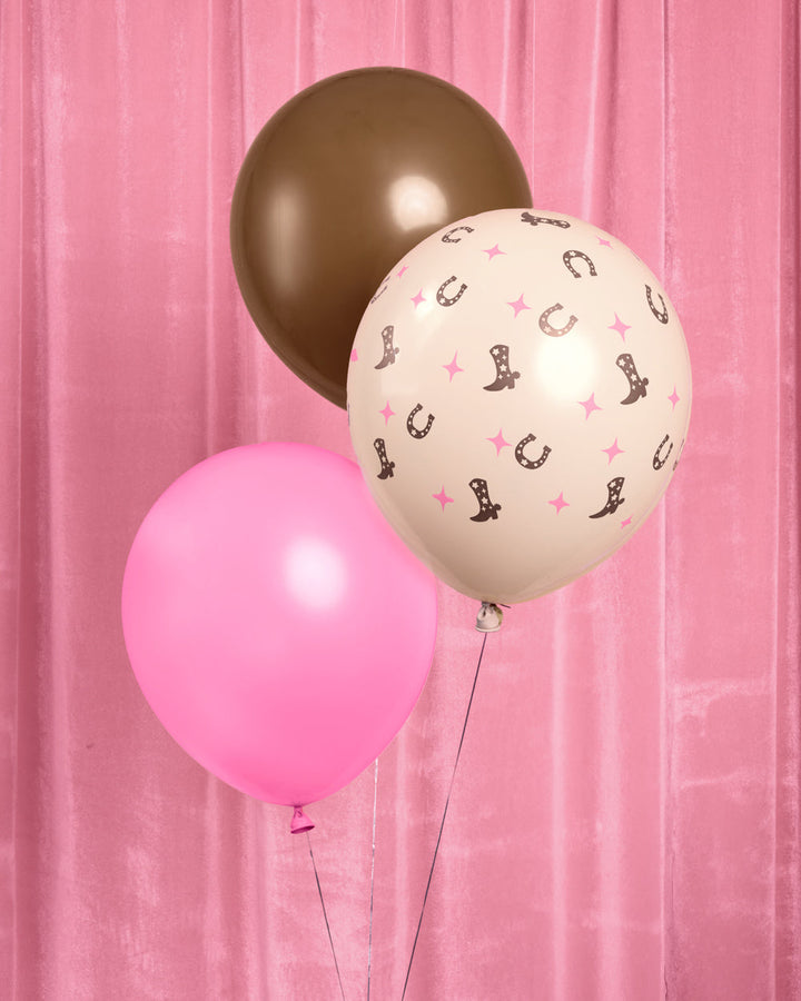 Bunch of pink and brown cowgirl latex balloons against a pink backdrop
