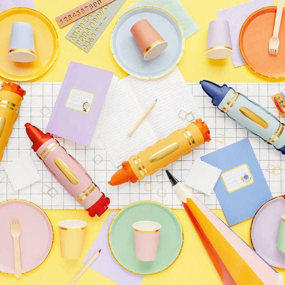Back to school party table flat lay with crayon balloons, plates, cups, and notebooks