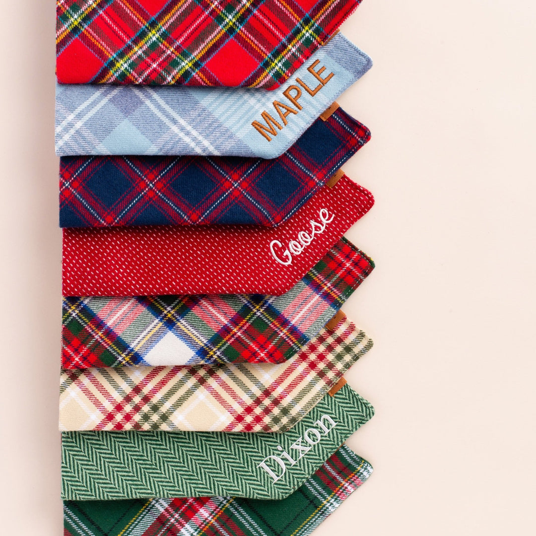 Stack of folded flannel bandanas in plaids and solids, some stitched with sample names