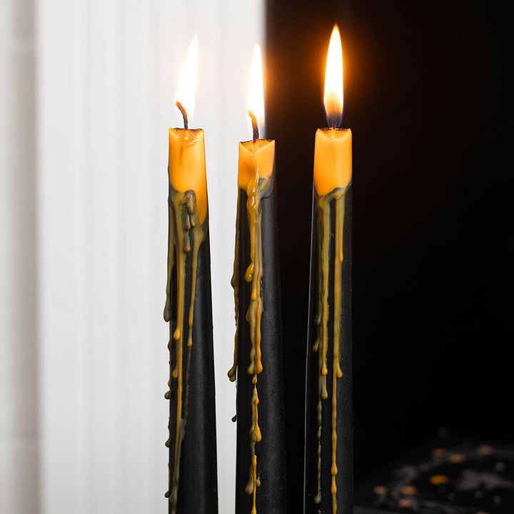 Three lit black tapers oozing orange wax down their sides, a glowing centerpiece for a spooky dinner table