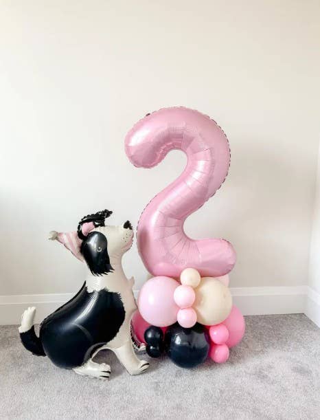 Shepherd dog balloon beside a pink number two balloon tower at a puppy party