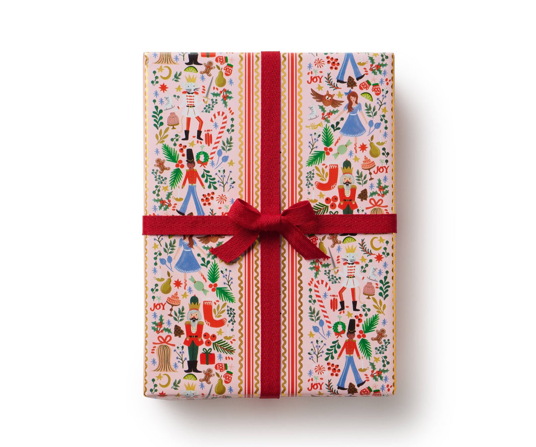 Holly Jolly Nutcracker wrapping paper on a wrapped gift, blush ground with nutcracker figures and gold accents