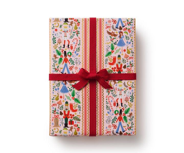 Holly Jolly Nutcracker wrapping paper on a wrapped gift, blush ground with nutcracker figures and gold accents