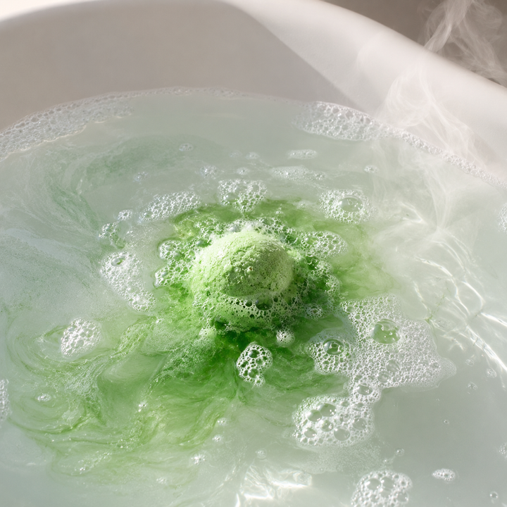 Green mini bath bomb fizzing in a steamy tub with swirls of color, a cozy holiday bath night