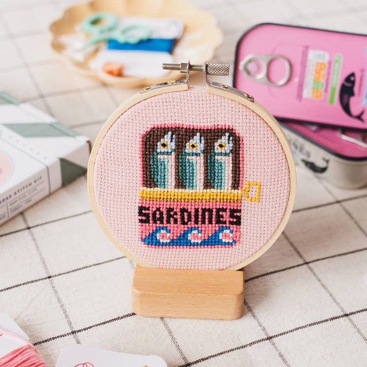 Finished sardines cross stitch hoop styled on checked cloth for coastal kitchen decor