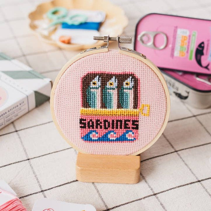 Finished sardines cross stitch hoop styled on checked cloth for coastal kitchen decor