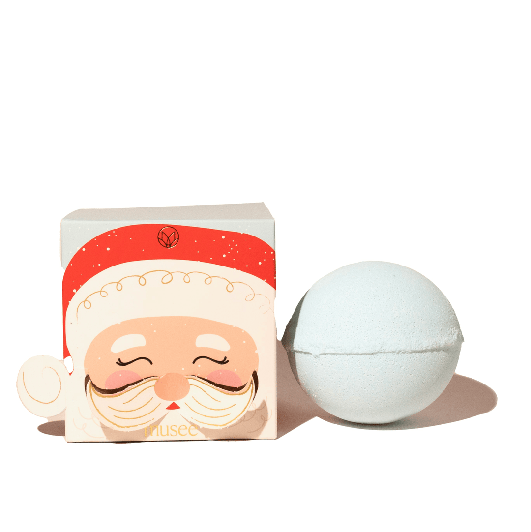 Pale blue bath bomb beside Musee Santa face box with red hat, a Christmas stocking stuffer for kids